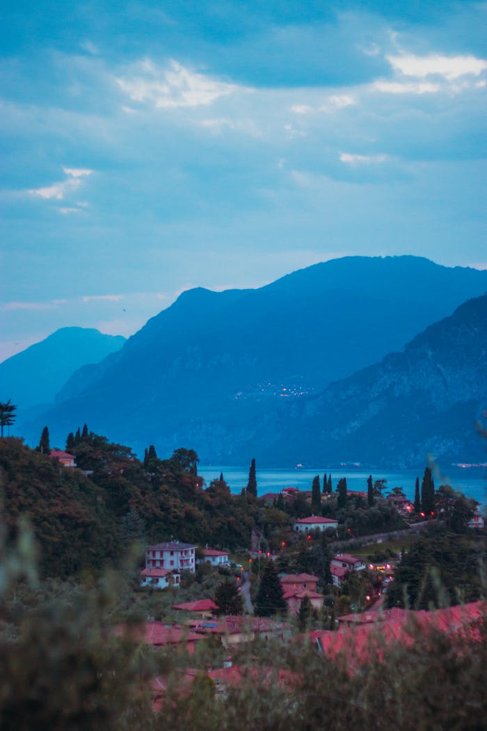 A beautiful panoramic view of Malcesine with Lake Garda and surrounding mountains at twilight.