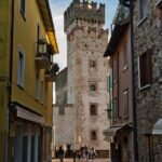 Charming view of a narrow alleyway leading to the historic Sirmione Castle in Italy.