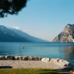 Tranquil view of Lake Garda with majestic mountains and clear sky, Italy.
