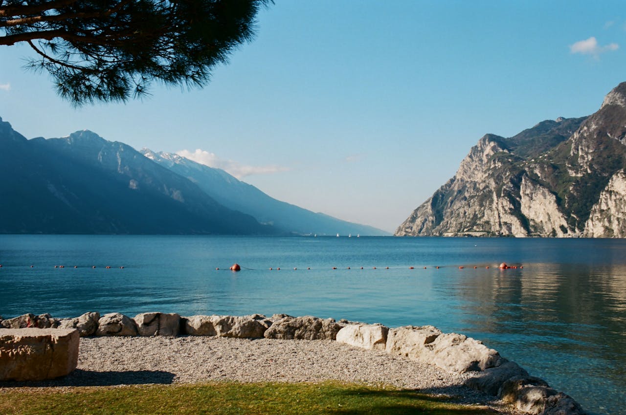 Tranquil view of Lake Garda with majestic mountains and clear sky, Italy.