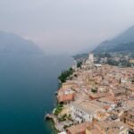 Scenic aerial view of Malcesine by Lake Garda with mountains in the background on a foggy day.