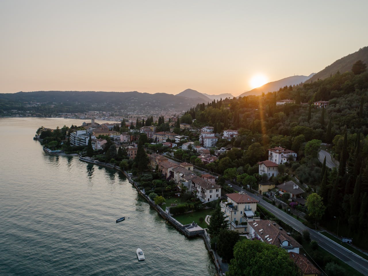 A scenic aerial shot of Salo, Italy on Lake Garda during sunset, showcasing waterfront and mountains.