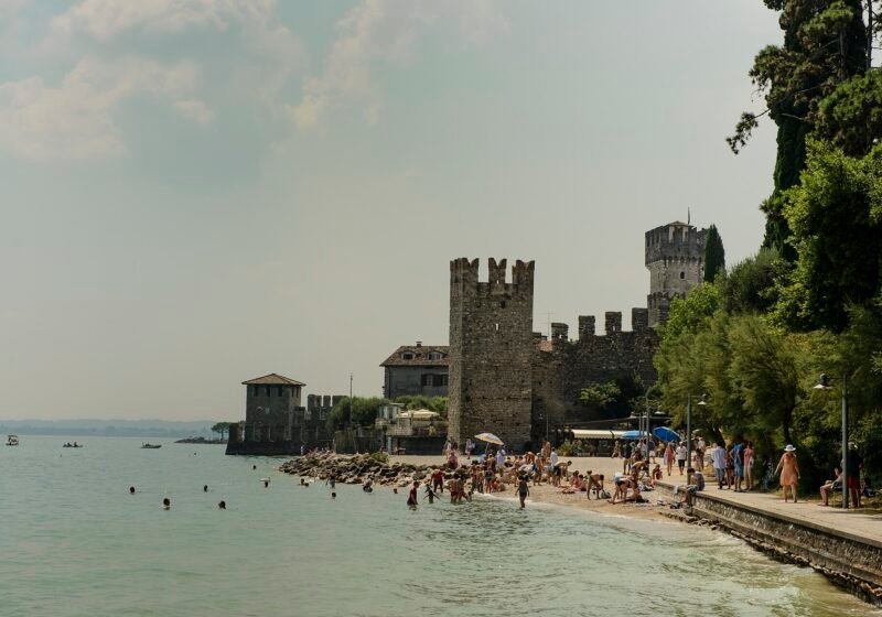 Bathers on the beach below the walls and towers of the Scaliger castle at Sirmione